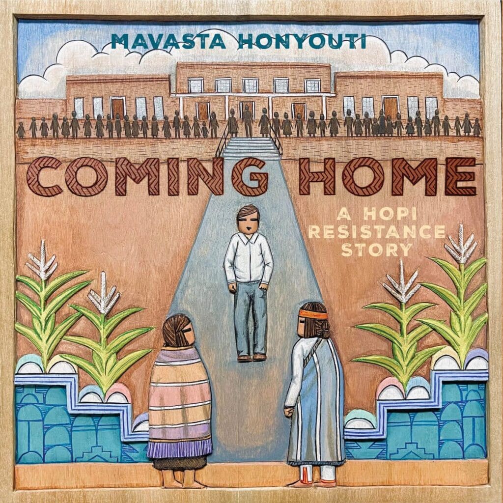 a young man wearing a white shirt and blue jeans walks towards two Native American elders wearing traditional dress