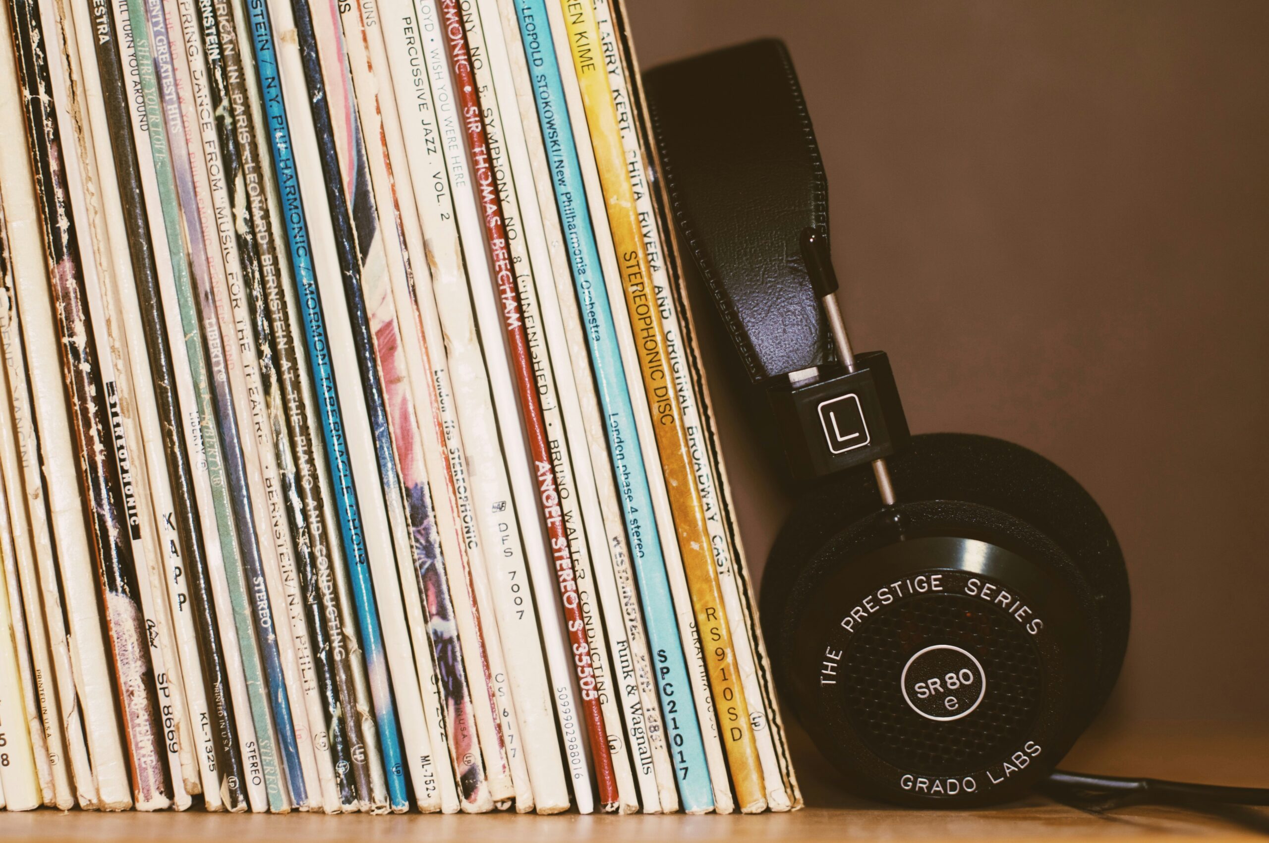 a pair of black headphones leans against a stack of vinyl records
