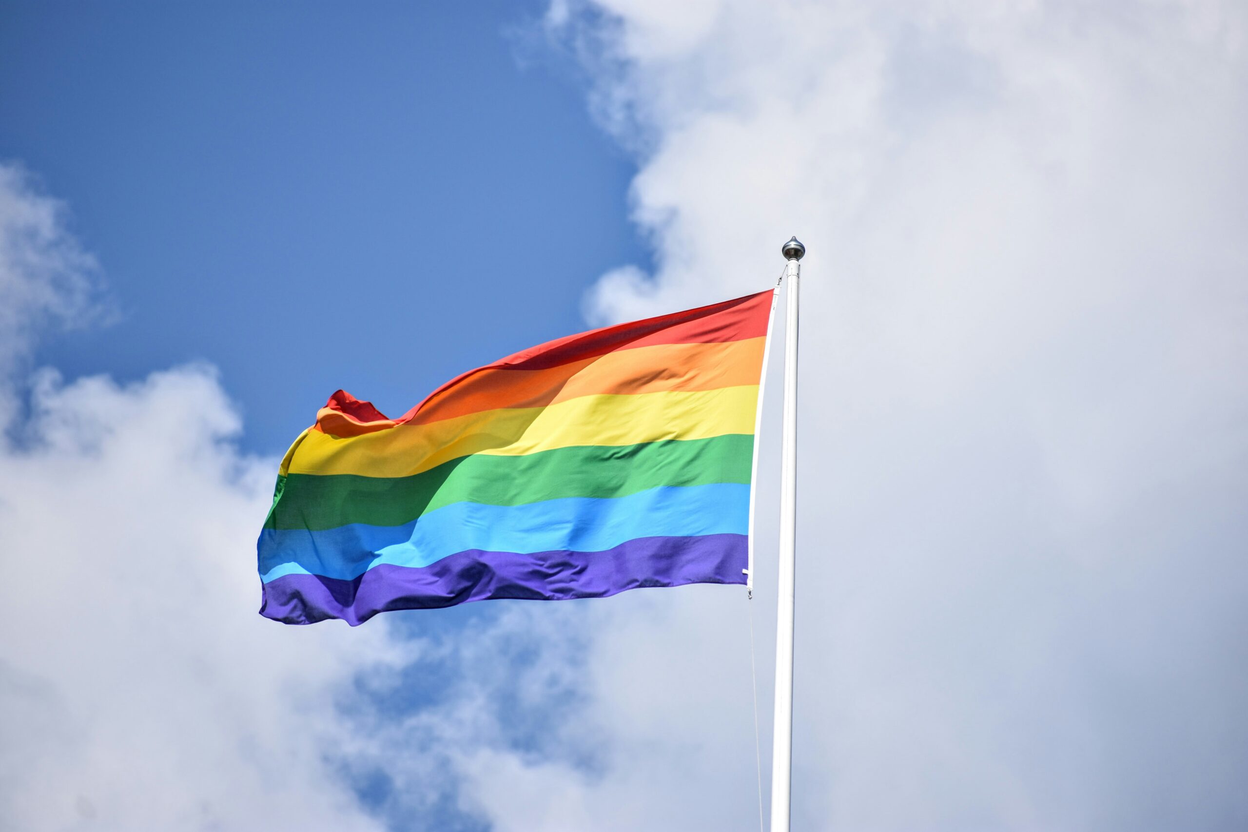 a rainbow flag waves proudly on a tall flag pole