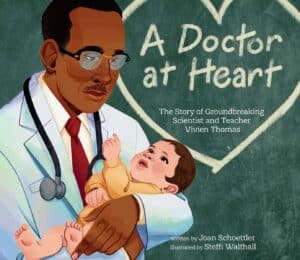 Black Dr Vivien Thomas holds a white baby. The baby is pointing up at him