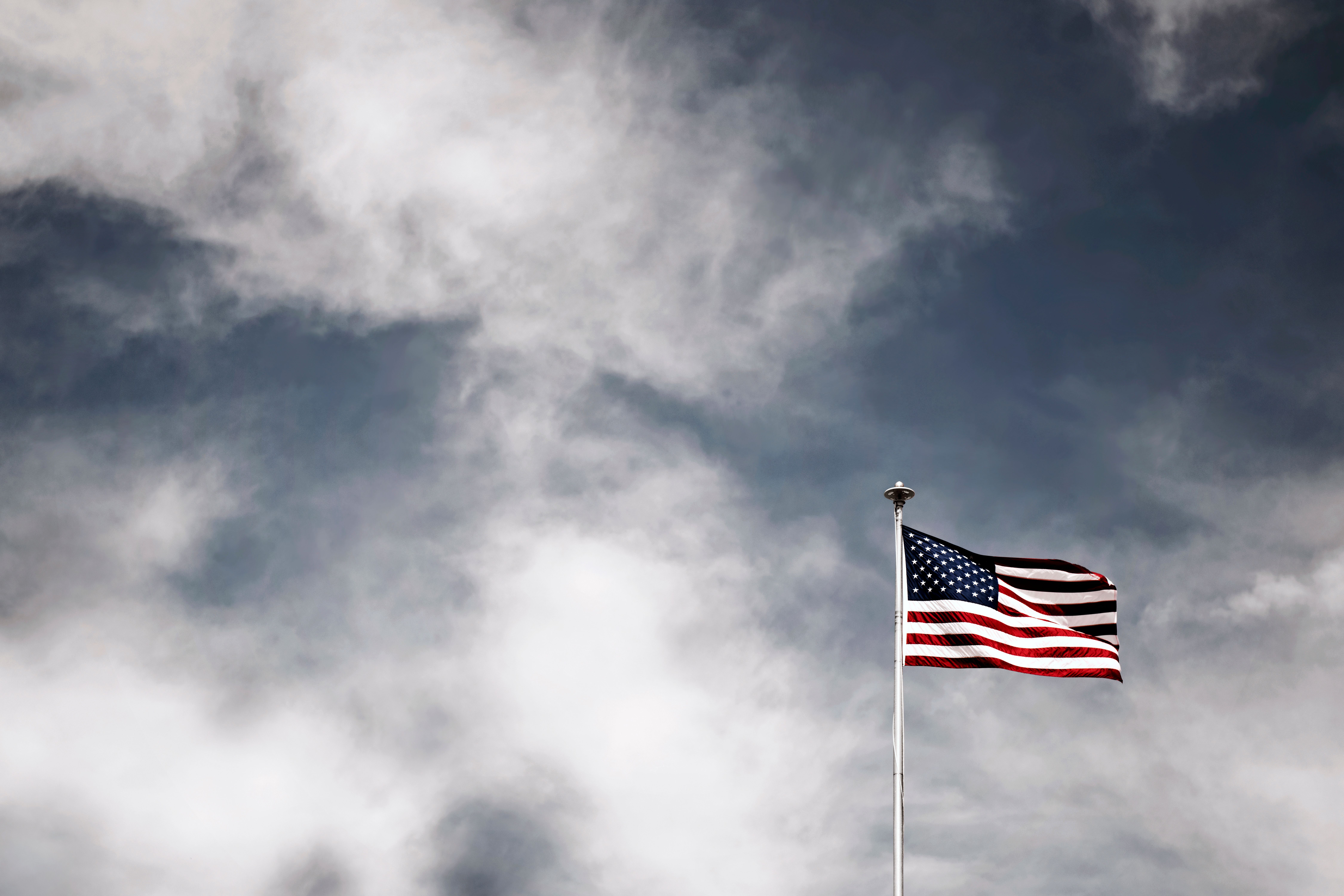 an american flag waves against a grey sky