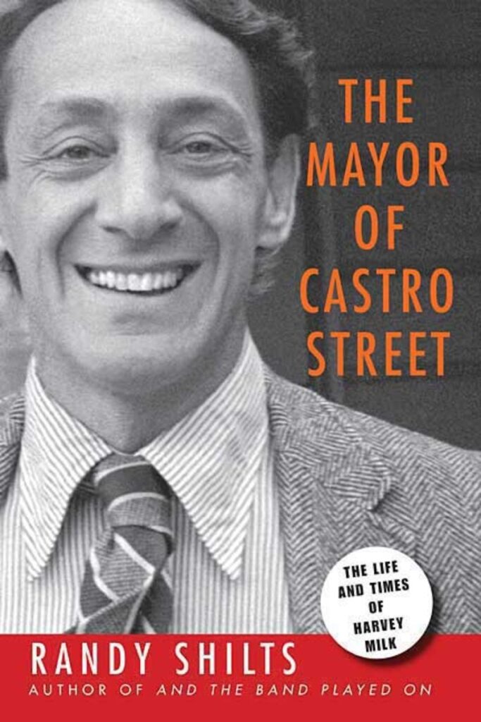 The cover photo of the book The Mayor of Castro Street shows a black and white photo of Harvey White wearing a suit jacket, striped button-down shirt, and a patterned tie, smiling at the camera