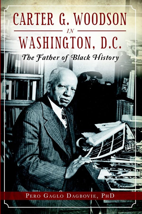 a black and white photo of Dr. Carter Woodson, wearing a suit, vest, and tie, as he sits at a desk covered in photos and pages. Above him says "Carter G. Woodson in Washington D.C. the Father of Black History"