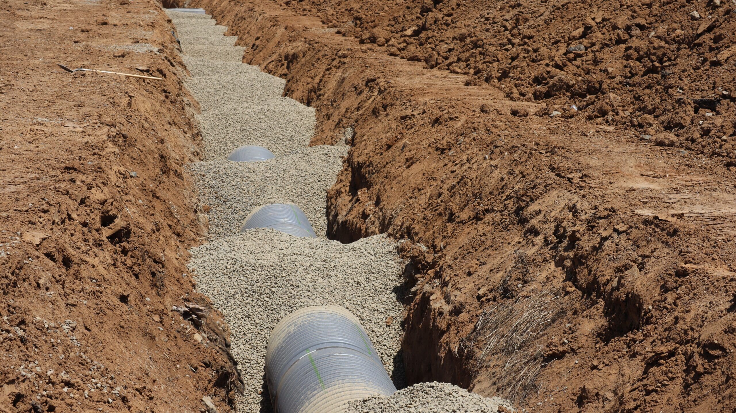 a pipeline similar to the Dakota Access Pipeline lays underground, partially covered with gravel
