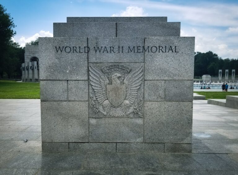a large stone World War II memorial stands tall, at the center is an eagle with a plaque in the center. Above the eagle is a banner that says "e pluribus unum". The Black veterans were often excluded from access to the G.I. Bill Benefits.