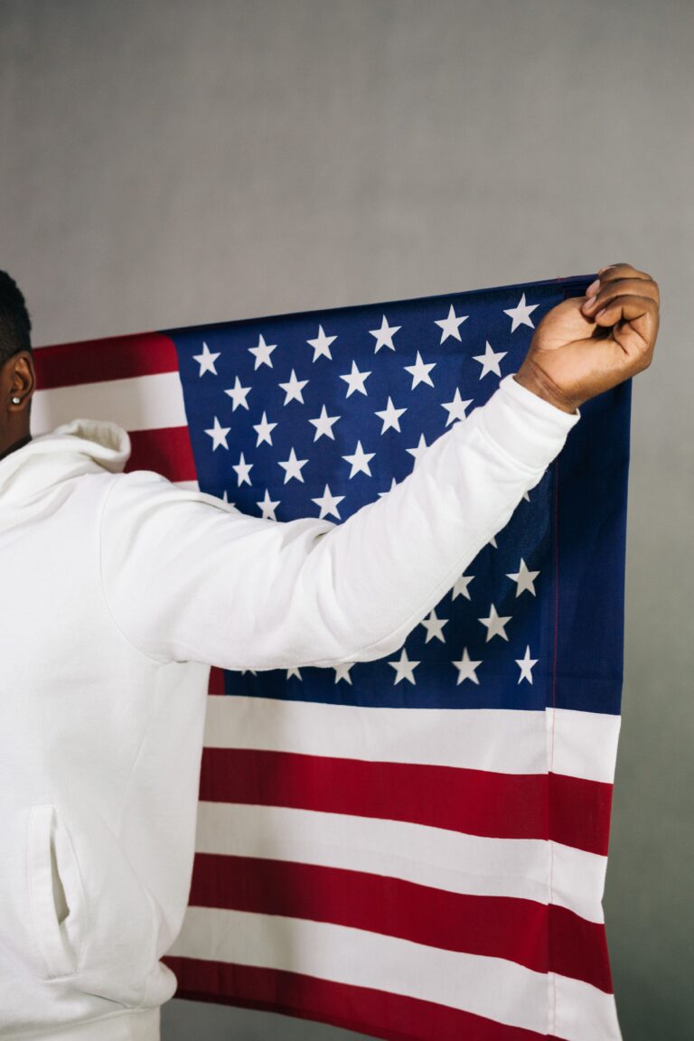 a Black man holds an American flag behind his back