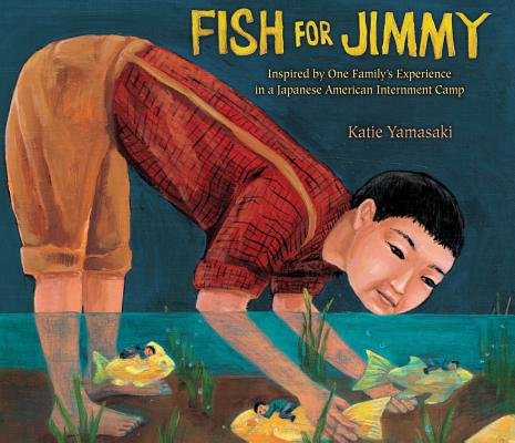 a young Japanese boy bends over in the water to grab fish